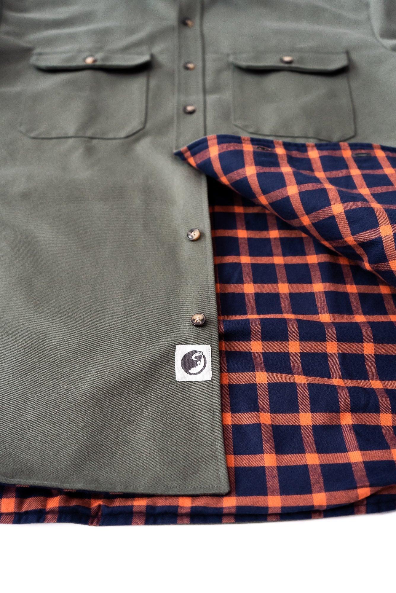 Green jacket with plaid lining and visible brand logo on a white background
