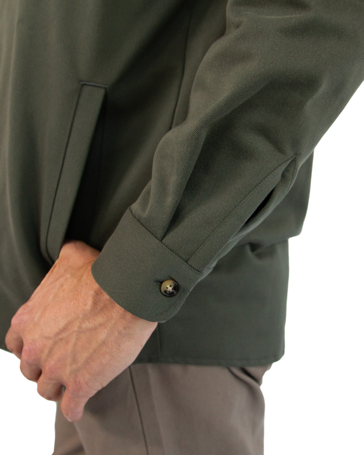 Close-up of a person wearing a green jacket with a button on a white background
