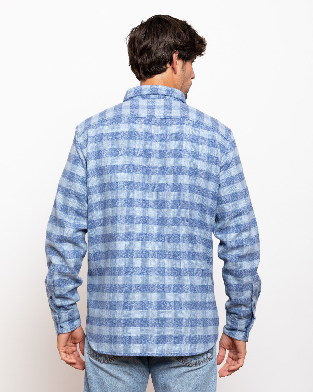 Man wearing a blue plaid shirt against a white background