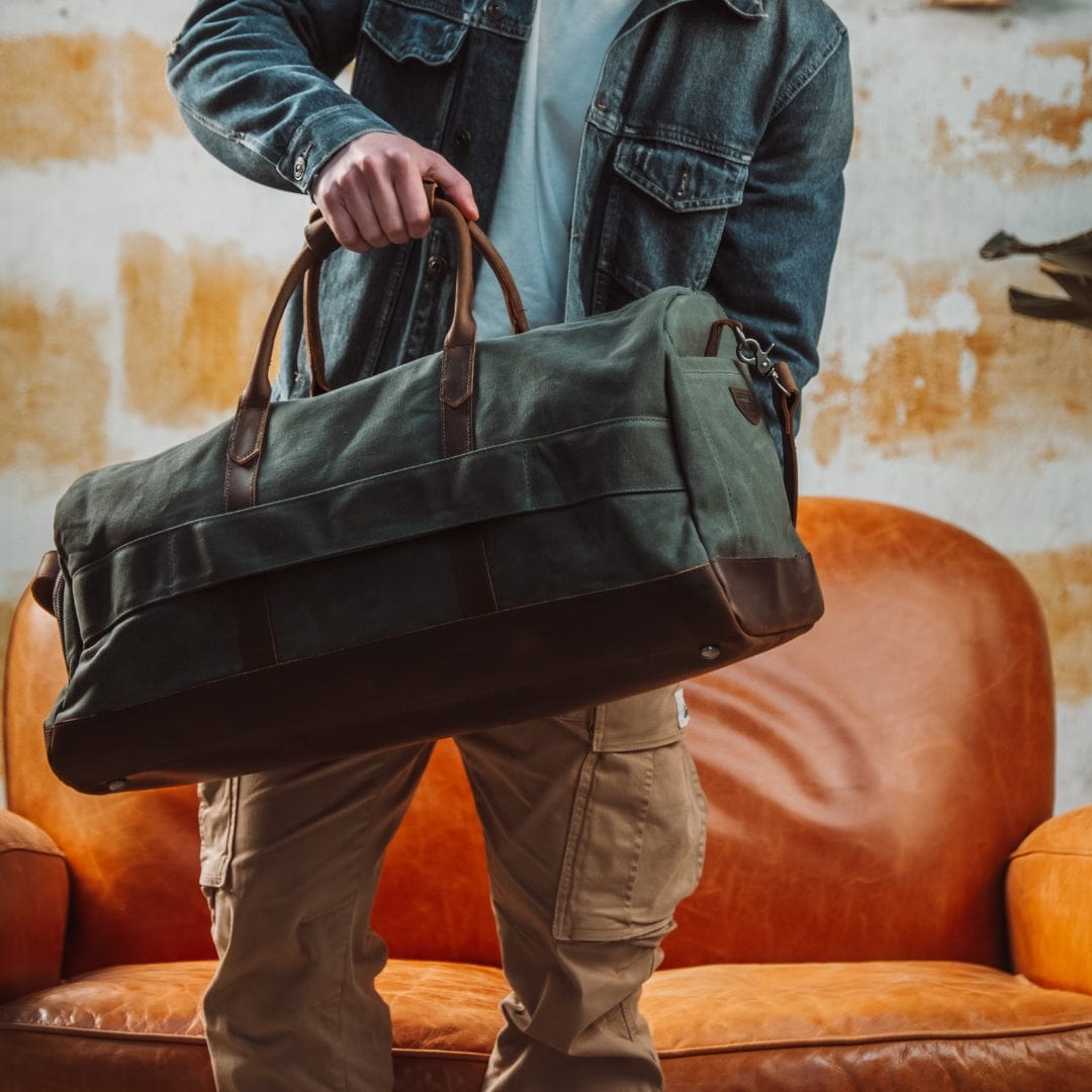 Dad holding a green duffel bag in front of an orange couch.